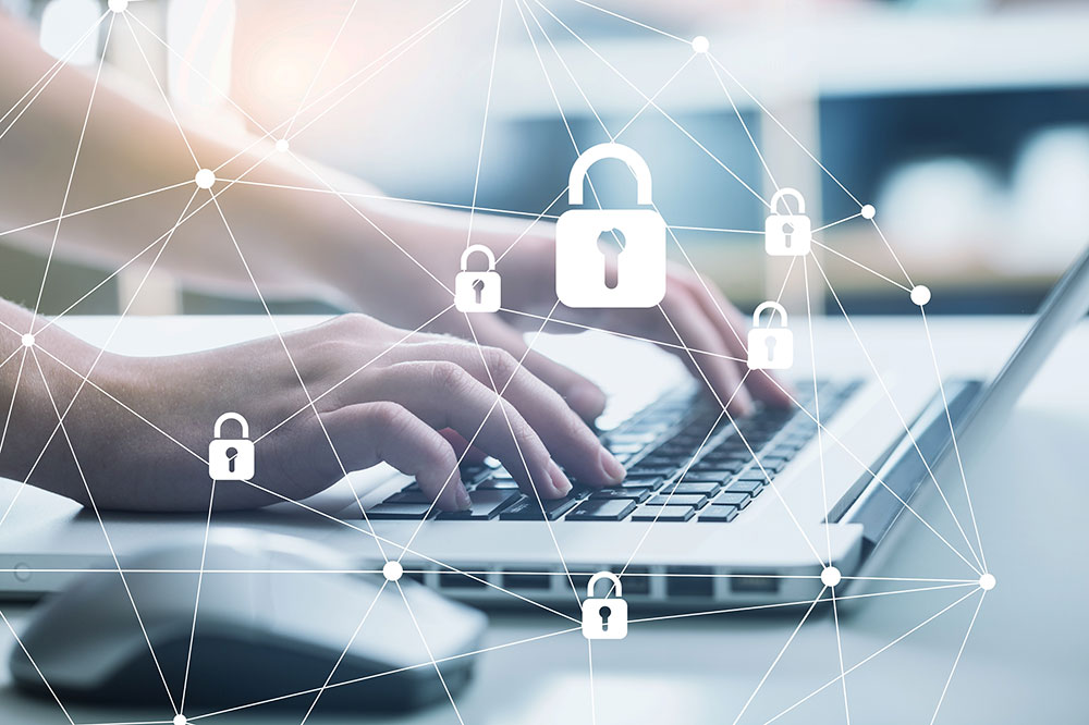 Main sur ordinateurs et cadenas pour symboliser la RGPD